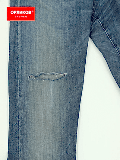 Синие мужские джинсы после штопки разрыва на штанине